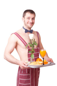 Attractive man in an apron with breakfast on a tray